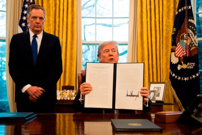 Trump holding up a signed order in the White House Oval Office, flanked by then-US trade representative Robert Lighthizer